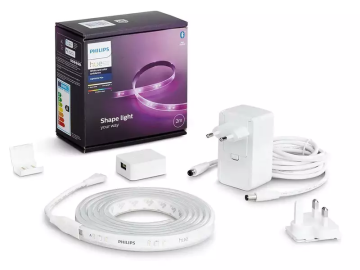 Philips Hue Lightstrip Plus: Verpackung, LED-Streifen auf Rolle, Netzteil, Adapter und Zubehör. Das Produkt ist weiß und schwarz.