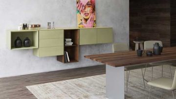 Wohnraum mit Esstisch und Wandregal in Grün- und Holztönen. Darüber ein buntes Gemälde. Beige Stühle und ein Teppich sind sichtbar.