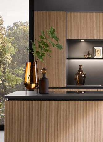 Moderne Küche mit schwarzer Arbeitsplatte und hellen, strukturierten Holzfronten ohne Griff