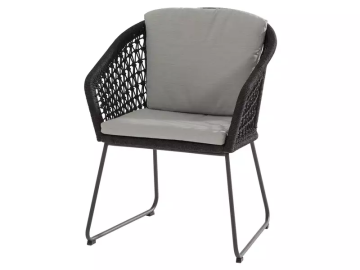 Ein Stuhl mit grauem Sitz- und Rückenkissen, dunklen Armlehnen im Flechtmuster und dunklem Metallgestell vor weißem Hintergrund.